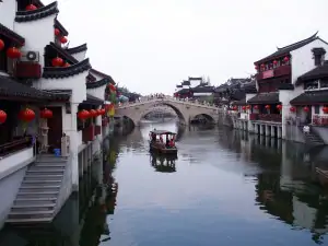 example of peaceful and harmonious Chinese culture photo of a gondola like boat in water between historic buildings on a cloudy day